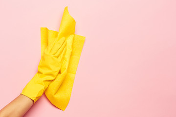 The woman's hand cleaning on a pink background. Cleaning or housekeeping concept