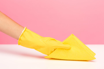 The woman's hand cleaning on a pink background. Cleaning or housekeeping concept