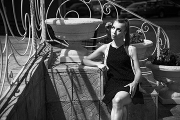 A stylish woman sitting on the steps. A pretty young stylish woman sitting on the concrete steps and looking aside.