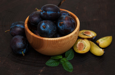 Bowl with  plums with green leaves