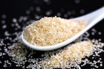 Full spoon of sugar isolated on black background.
