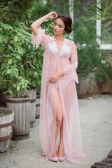Beautiful lady poses in pink robe in the garden