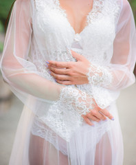 Woman in white lingerie and robe poses in the garden