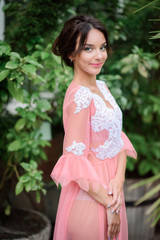 Naklejka premium Beautiful lady poses in pink robe in the garden