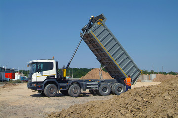 Dump truck unloading soil on construction site