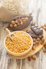 Corn kernels in wooden plates and popcorn with Caramel and chocolate cream on wooden table