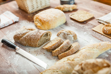 Fresh bread slice and cutting knife on rustic wooden table