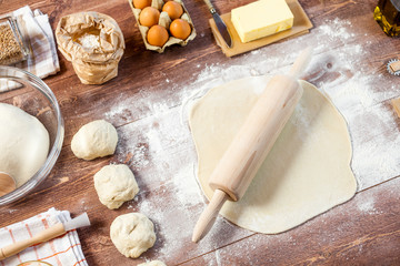 Rolled out dough on wooden table with rolling pin