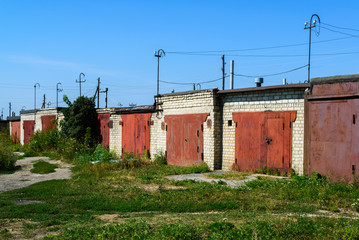 Fototapeta na wymiar Brick garages with red metal gates of garage cooperative