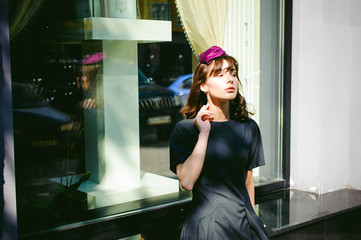 Beautiful woman in a dark stylish dress strolls along the street, near boutiques. Portrait of a fashionable girl