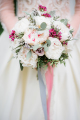 Bride holds rich wedding bouquet in her arms