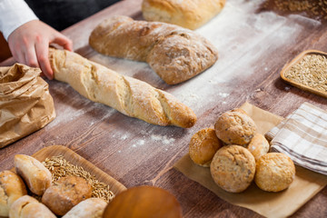 Naklejka premium Man holding bread on wooden table in a bakery close up