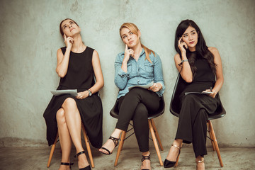 Portrait of three young pretty women sit on the chair and thinking an idea. 