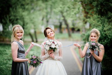 Fototapeta premium Pretty bride and bridesmaids pose in a green park