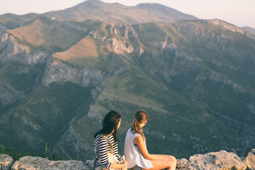 Naklejka premium Mother and daughter looking on mountain peak, whilst resting