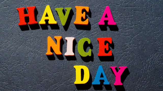 The expression "Have a nice day" made of colorful wooden letters on a dark table.