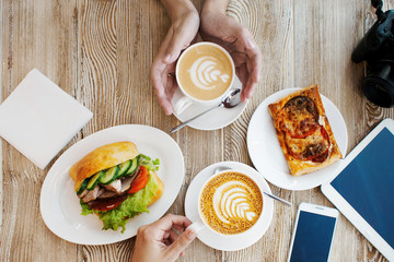 Two cups of coffee, friendly atmosphere. Chicken sandwich, Cup of coffee and smartphone on the table