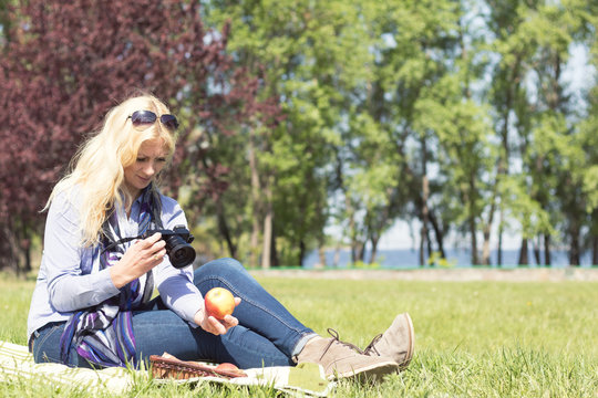 Professional woman photographer. Woman takes photo of apple. rofessional woman photographer taking outdoor with prime lens, during a sunny day in the spring park.