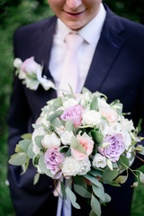 Groom holds tender wedding bouquet of roses
