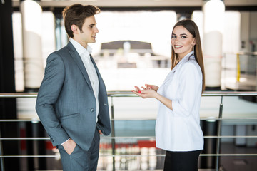 Smiling businesswoman telling something to her colleague in the office. Business man speak with business woman in office