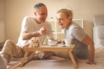 Senior couple having healthy breakfast together in bed. - Powered by Adobe