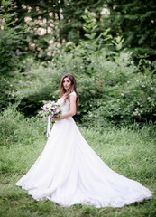 Obraz na płótnie Canvas Tender bride in a long dress poses in a green garden