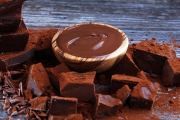 Chocolate cream melted, chocolate pieces and chocolate powder on wooden table