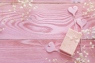 Pink background with gift box and delicate little white flowers. Copy space.