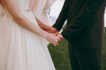 Loving bride and groom tenderly hold hands