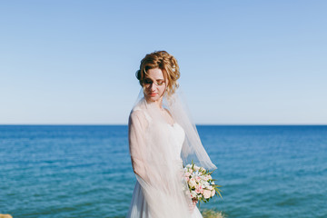 Fototapeta na wymiar Beautiful blonde bride on a walk by the sea