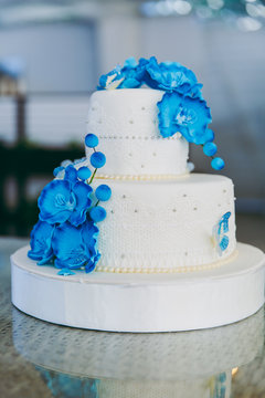 Wedding white cake with blue flowers is on the table