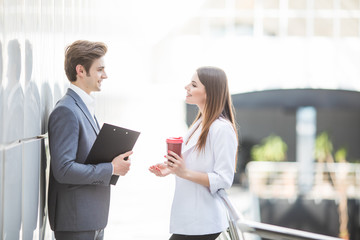 Two Business Colleagues standing in office hall having informal discussion with coffee