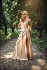 Obraz na płótnie Canvas Girl in a long dress in the park. Blonde. Summer.
