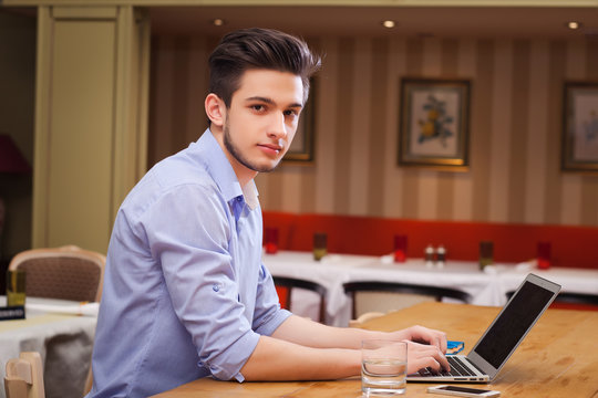 Young guy working on laptop in the Italian style kitchen