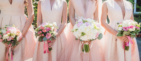 Bride and bridesmaids hold wedding bouquets in their hands