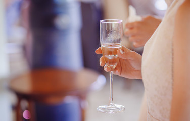 Bride holds a glass of champagne in her tender arms