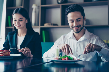 Lunch together. Two young cute lovers are sitting in a fancy restaurant, wearing smart outfits and eating delicious salad and a dessert, smiling.