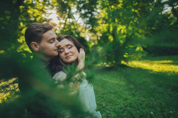  Handsome young man standing in park  and kissing his girlfriend on forehead