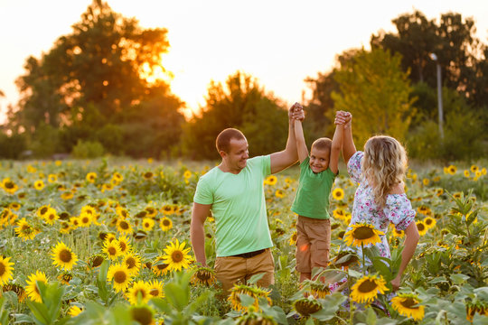 beautiful family holds a baby son in a sunflower field. tenderness, smiles, happiness