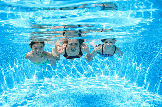 Family swims in pool under water, happy active mother and children have fun underwater, fitness and sport with kids on summer vacation
