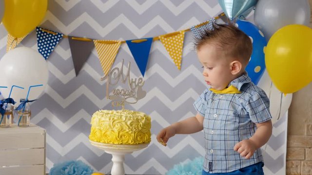 A toddler puts a finger inside a birthday cake. 