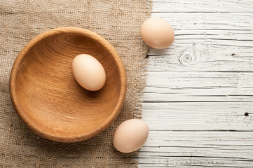 chicken eggs in wooden plate on white wooden background
