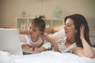 Mother and her little baby at home. Mother with her baby watching something on digital tablet.