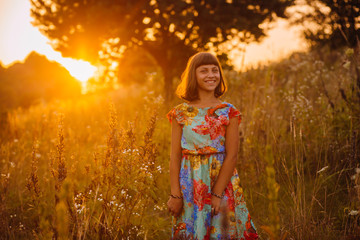 Obraz premium Pretty girl in a bright dress poses on the field