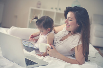 Mother and her little baby at home. Mother and baby using technology.