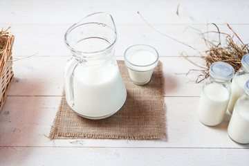 milk and glasses of milk on a wooden rustic table.