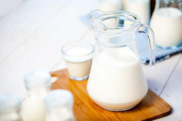 milk and glasses of milk on a wooden rustic table.