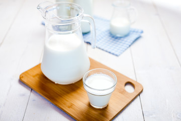 milk and glasses of milk on a wooden rustic table.