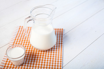 milk and glasses of milk on a wooden rustic table.