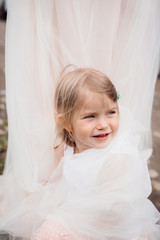 Little girl sits enveloped in mother's skirt